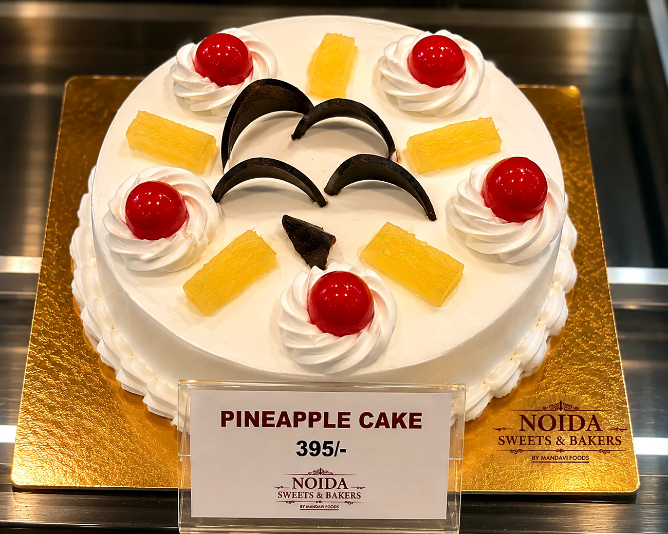 Pineapple cream cake with fresh fruit crown — made at Noida Sweets and Bakers